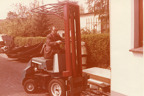 Unternehmensgründer Egon Hirsch auf einem historischen Gabelstapler vor dem Betriebsgelände in Bremen